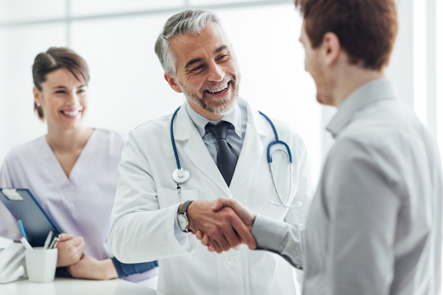 62025951 - smiling doctor at the clinic giving an handshake to his patient, healthcare and professionalism concept